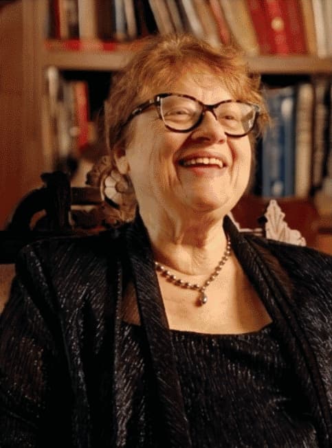 Janice Stauffer smiling in conversation, in front of a bookshelf